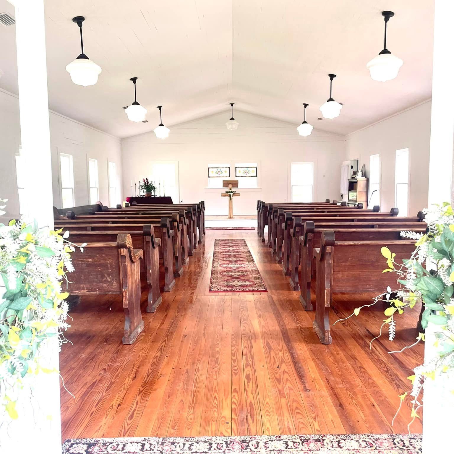 Looking through the chapel doors down the aisle between the old wooden pews to the cross at the front